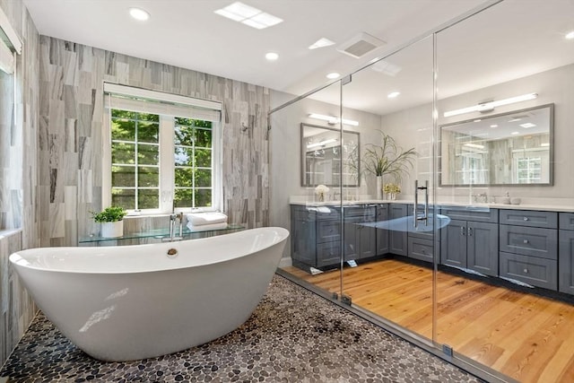 full bath with a freestanding tub, recessed lighting, tile walls, and vanity