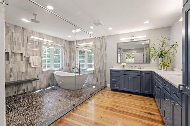 full bathroom with a freestanding bath, wood finished floors, vanity, and recessed lighting