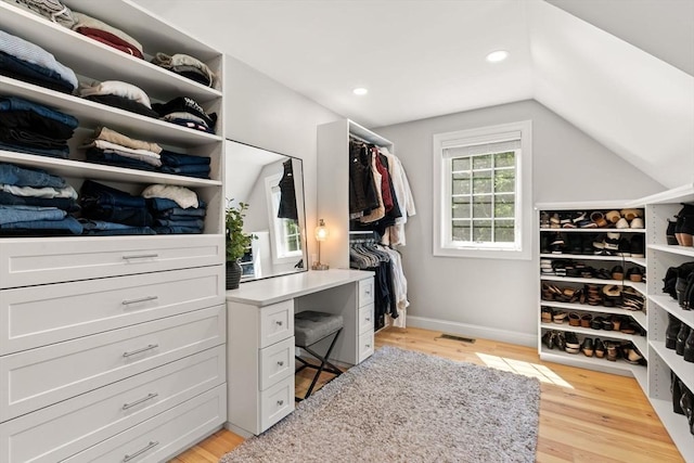 walk in closet with light wood-type flooring and lofted ceiling