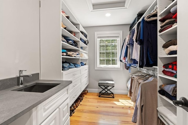 spacious closet with a sink, attic access, and light wood-style floors