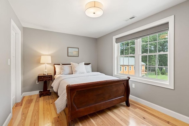 bedroom featuring light wood finished floors, visible vents, and baseboards