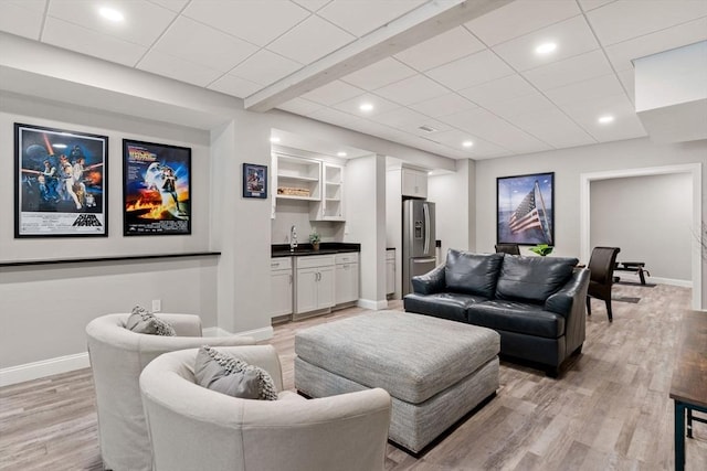 living room with wet bar, light wood-style flooring, and baseboards