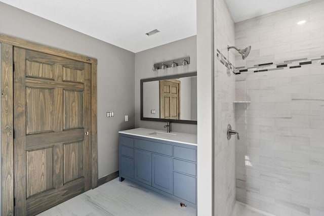 bathroom featuring marble finish floor, visible vents, a tile shower, and vanity