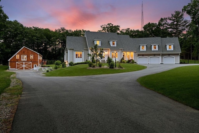 view of front facade with a garage, a yard, aphalt driveway, and a barn