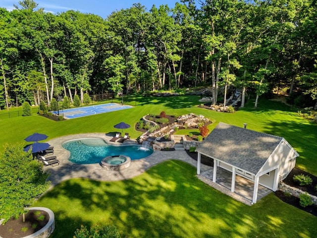 view of swimming pool with a pool with connected hot tub, fence, and a lawn