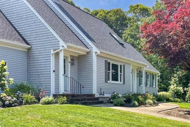 view of front of house featuring entry steps, a shingled roof, and a front lawn