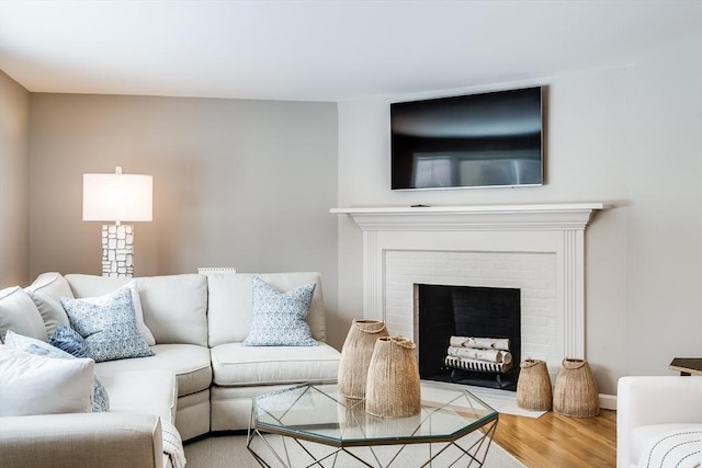 living room with a brick fireplace and wood finished floors