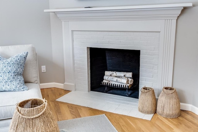 interior details featuring a brick fireplace, wood finished floors, and baseboards