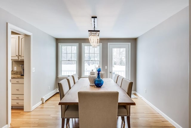 dining area featuring light wood-style flooring, baseboards, baseboard heating, and a chandelier