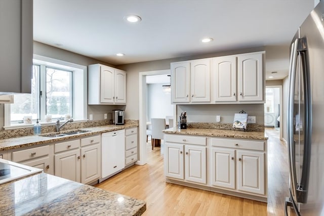 kitchen with white dishwasher, white cabinetry, and freestanding refrigerator