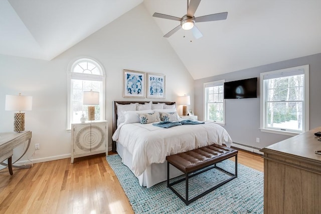 bedroom with a baseboard heating unit, light wood-type flooring, and multiple windows