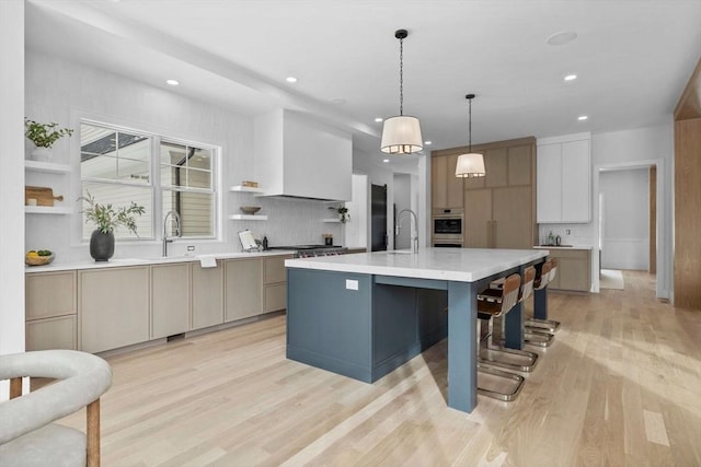 kitchen featuring light wood-type flooring, hanging light fixtures, a large island, and appliances with stainless steel finishes