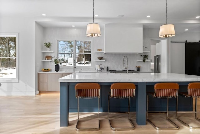 kitchen with a barn door, white cabinetry, hanging light fixtures, and a kitchen bar