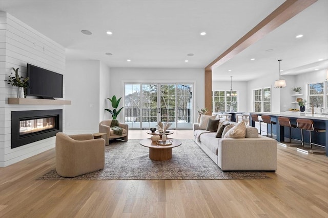 living room with sink, light hardwood / wood-style flooring, and a fireplace