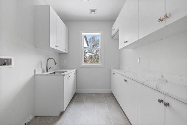 washroom with cabinets, sink, hookup for a washing machine, and light tile patterned flooring