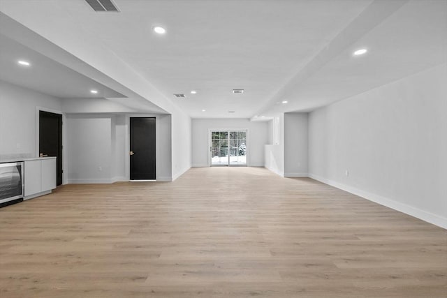 unfurnished living room with wine cooler, bar, and light wood-type flooring