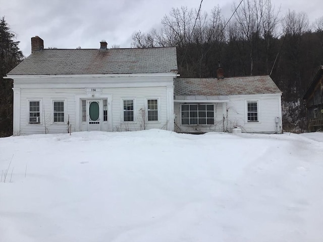 snow covered rear of property featuring a chimney