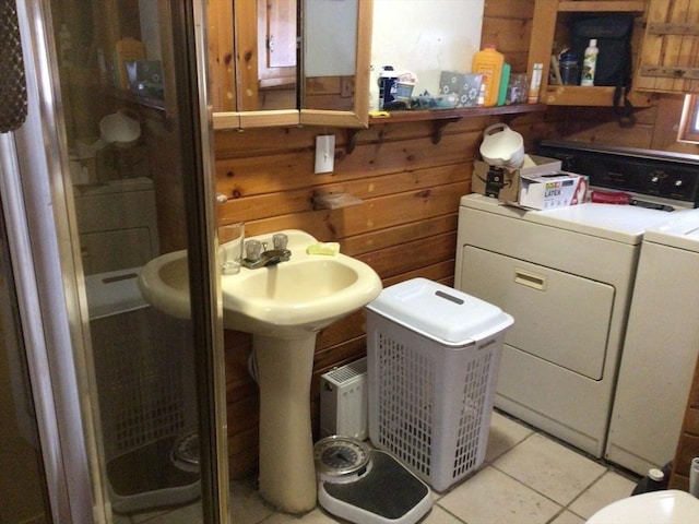 full bath featuring washing machine and dryer, tile patterned flooring, wooden walls, and a shower stall