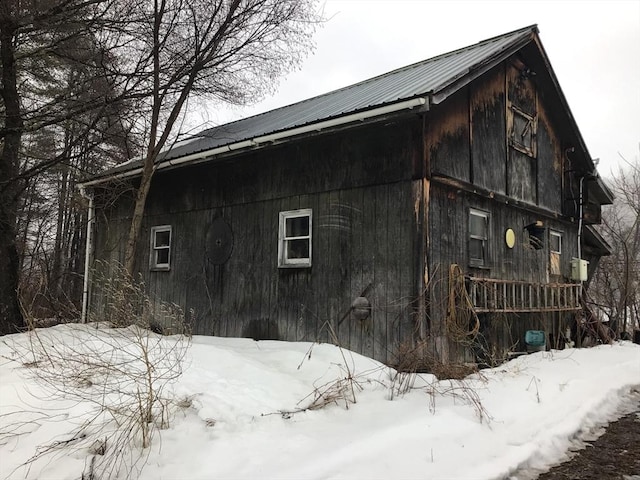 view of snow covered exterior with metal roof and a barn