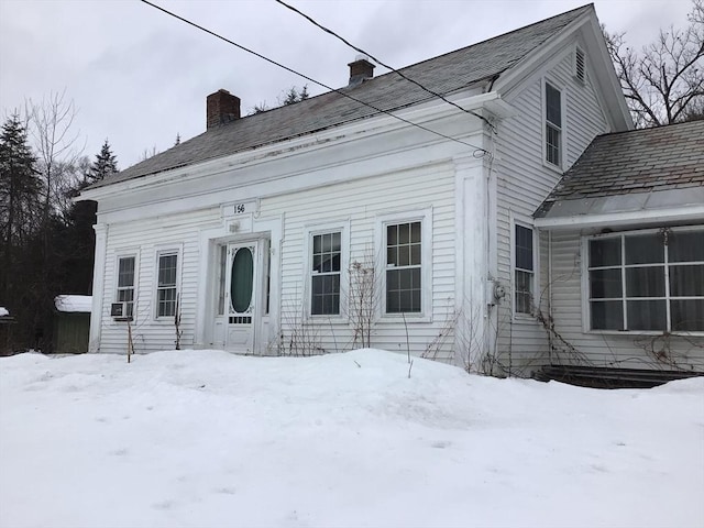 snow covered back of property featuring a chimney