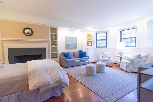 living room featuring a baseboard radiator, wood-type flooring, a fireplace, and recessed lighting