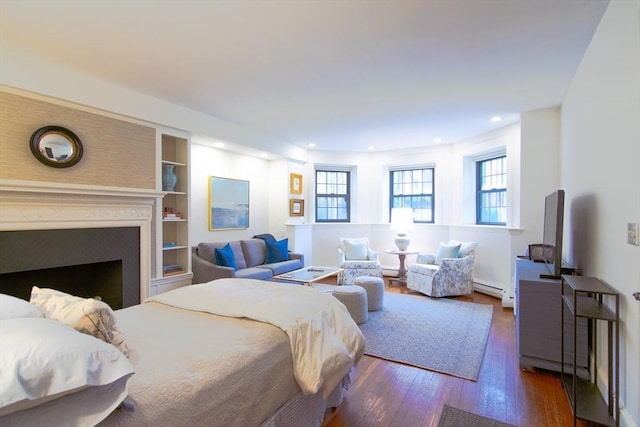 bedroom featuring a fireplace, recessed lighting, wood-type flooring, a baseboard radiator, and a baseboard heating unit