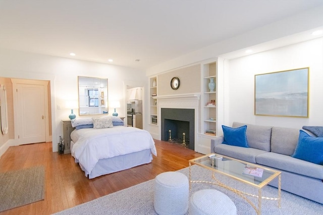 bedroom featuring recessed lighting, a fireplace, and wood finished floors