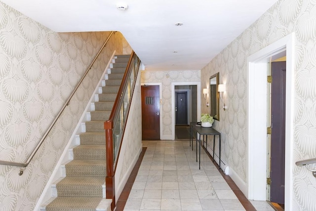 stairway featuring baseboards and wallpapered walls