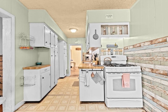 93 Warren, Fall River, MA 02721 - kitchen with white range with gas stovetop, light flooring, wood walls, a textured ceiling, and light countertops