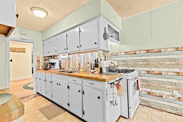 93 Warren, Fall River, MA 02721 - kitchen featuring white range with gas stovetop, light floors, a textured ceiling, wood walls, and a sink