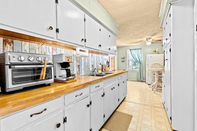 93 Warren, Fall River, MA 02721 - kitchen with a sink, a textured ceiling, light flooring, white cabinetry, and a ceiling fan