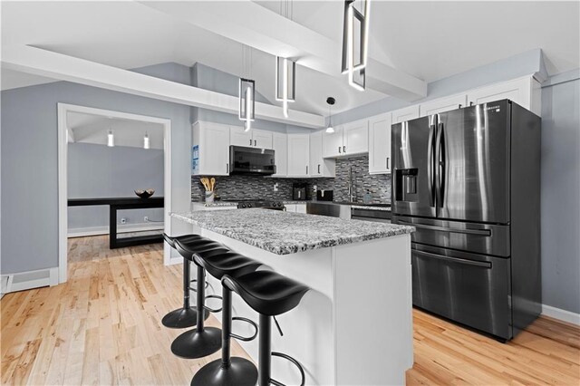 kitchen featuring light wood-type flooring, backsplash, and stainless steel fridge with ice dispenser