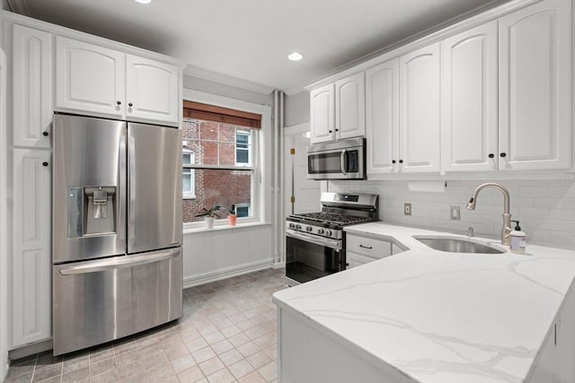 kitchen featuring light stone counters, a sink, white cabinets, and stainless steel appliances