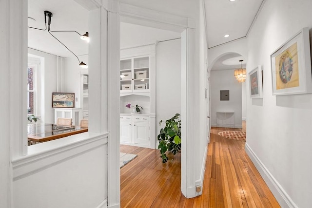 hall with recessed lighting, arched walkways, baseboards, and light wood finished floors