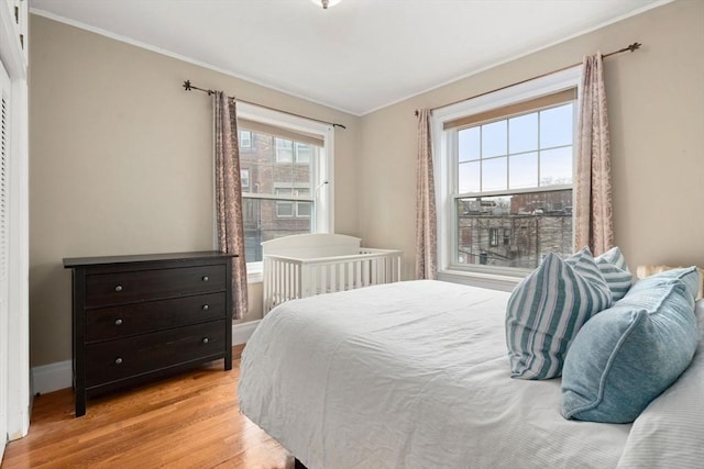 bedroom with crown molding, baseboards, and light wood finished floors