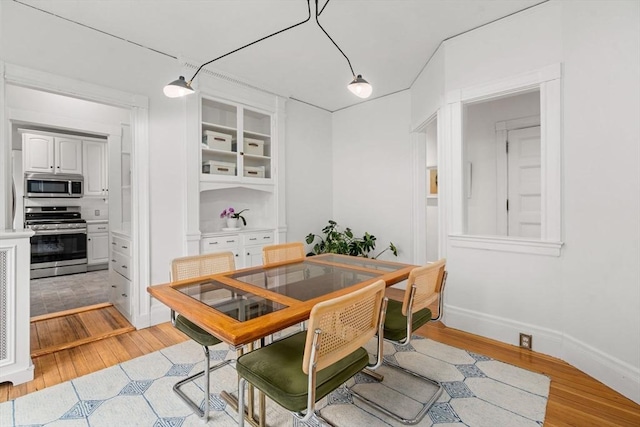 dining space featuring light wood-style floors and baseboards