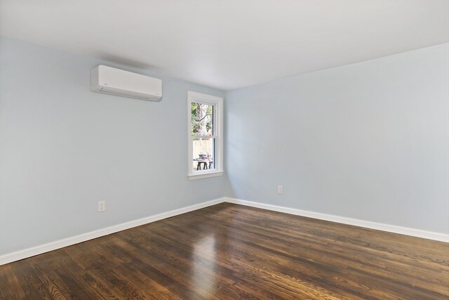 unfurnished room with an AC wall unit and dark wood-type flooring