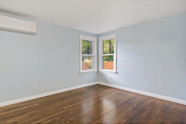 spare room featuring a wall mounted air conditioner and dark hardwood / wood-style floors