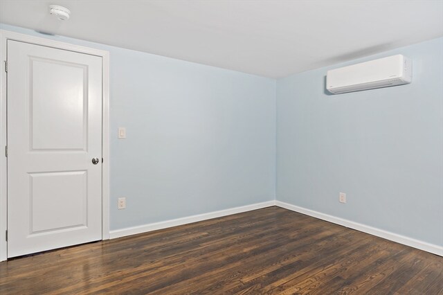 unfurnished room featuring dark wood-type flooring and a wall mounted AC