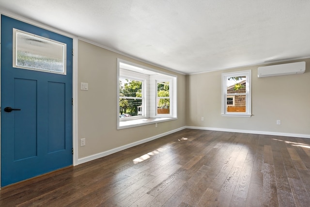 foyer entrance with crown molding, dark hardwood / wood-style floors, a wall mounted AC, and a wealth of natural light