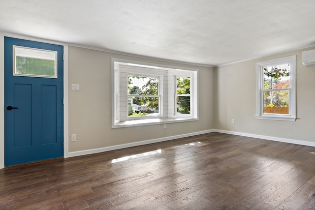 foyer entrance featuring an AC wall unit, ornamental molding, a textured ceiling, and dark hardwood / wood-style floors