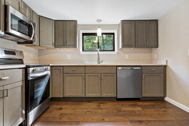 kitchen featuring dark wood-type flooring, stainless steel appliances, sink, and hanging light fixtures