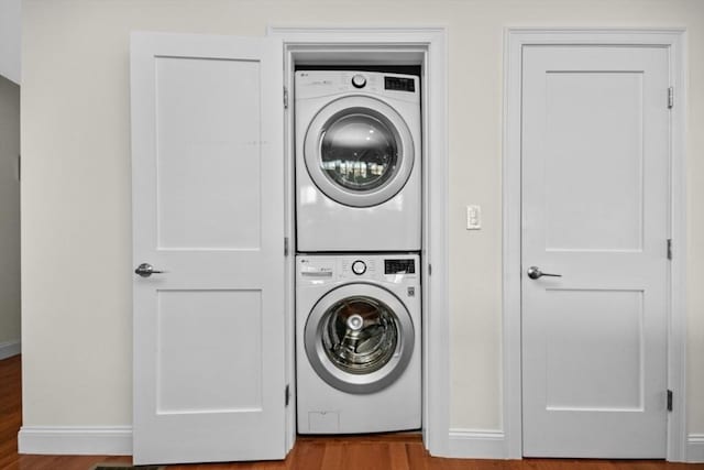 laundry area featuring stacked washing maching and dryer and hardwood / wood-style flooring