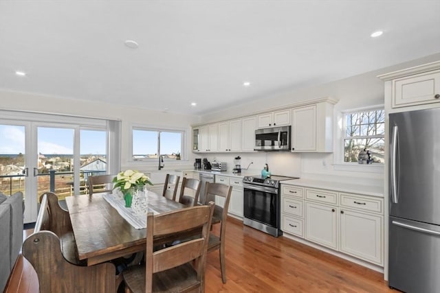 kitchen with hardwood / wood-style floors, white cabinets, appliances with stainless steel finishes, and french doors