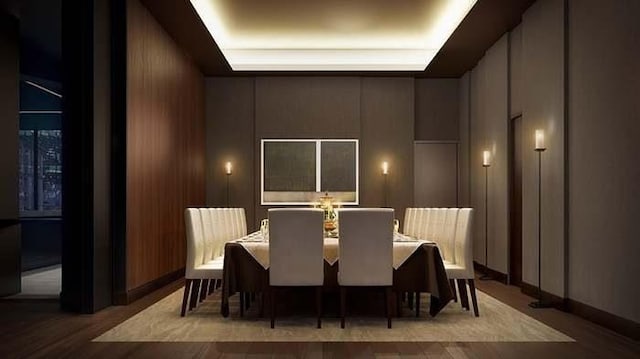 home theater room with wood-type flooring, a raised ceiling, and wood walls