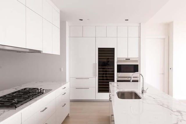 kitchen with light stone countertops, sink, white cabinetry, and stainless steel appliances