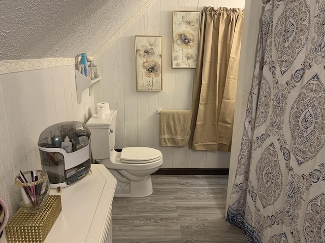 bathroom featuring wood-type flooring, wood walls, and toilet