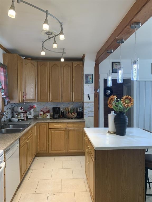 kitchen featuring white dishwasher, hanging light fixtures, light tile patterned floors, decorative backsplash, and sink