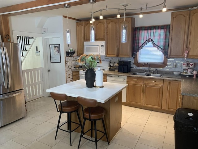 kitchen with white appliances, a center island, a kitchen bar, sink, and hanging light fixtures