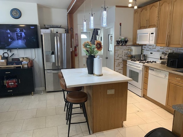 kitchen featuring hanging light fixtures, backsplash, light tile patterned floors, white appliances, and a center island